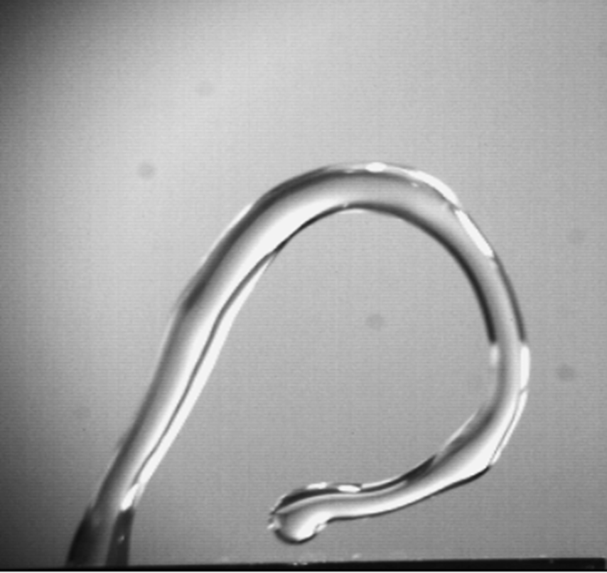 This is a picture from a high speed video showing jetting behaviour of a 20uL water droplet induced by ZnO surface acoustic waves (from left side). The jetting is induced by sub-nanometre amplitudes of surface acoustic waves interacting with water droplet, causing the droplet jetting along Rayleigh angle. However, due to a combination of acoustic pressure, internal flow, gravity force, surface tension and capillary, the droplet has been deformed significantly before fully jetted from substrates. (The photo is not a composite and has not been enhanced.)